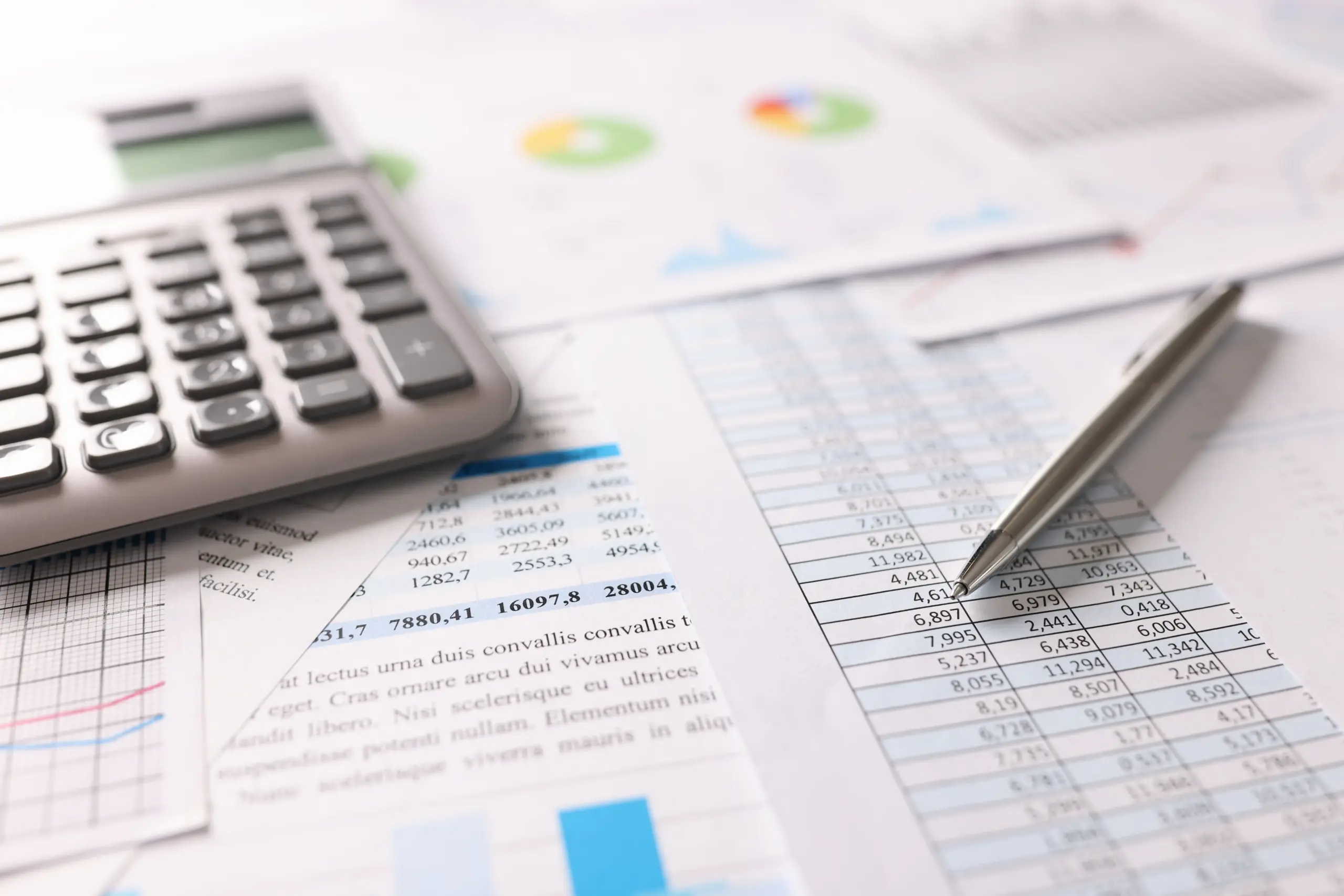 Taschenrechner und Stift für Finanzdokumente mit Diagrammen und Tabellenkalkulationen, die effektives Mahnwesen und Finanzanalysen unterstützen.
